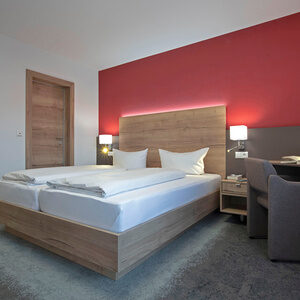 Der Schlafraum im Doppelzimmer Komfort Plus ist im rot wei&szlig;en Stil gehalten.